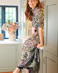 Woman in a floral dress standing in a kitchen.